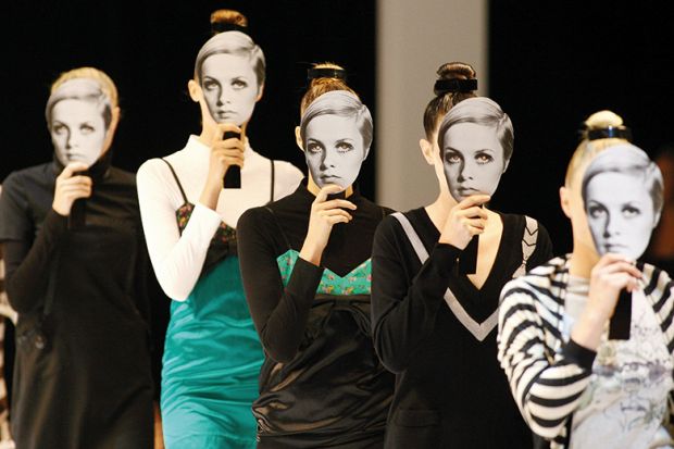 Models displaying cut out masks of former model 'Twiggy' parade outfits by Australian designers