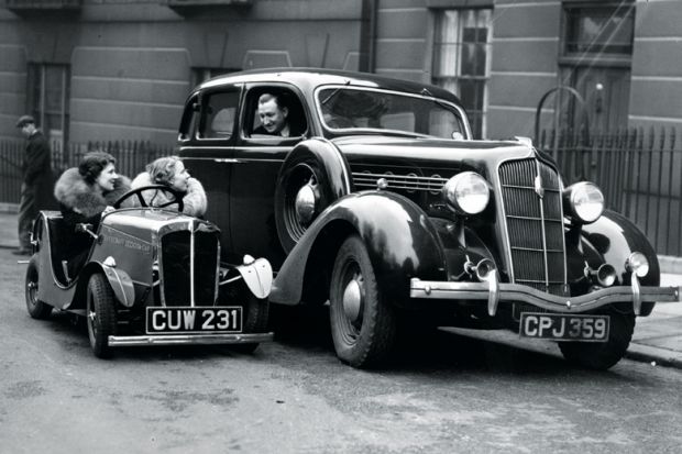 Women in small car looking at man in larger car