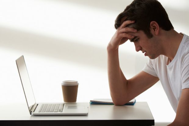 Unhappy male student looking at laptop