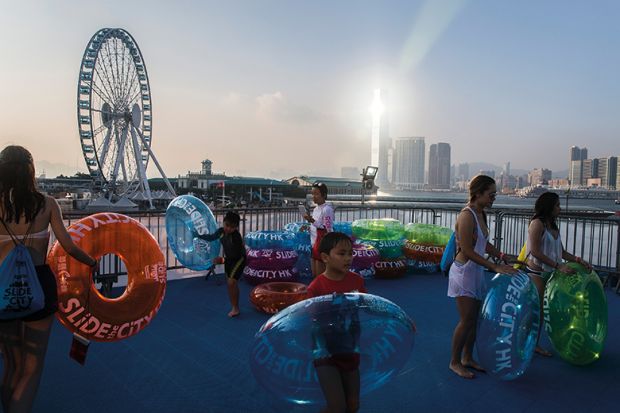 Participants wait with tubes to ride a giant waterslide in the Central district of Hong Kong