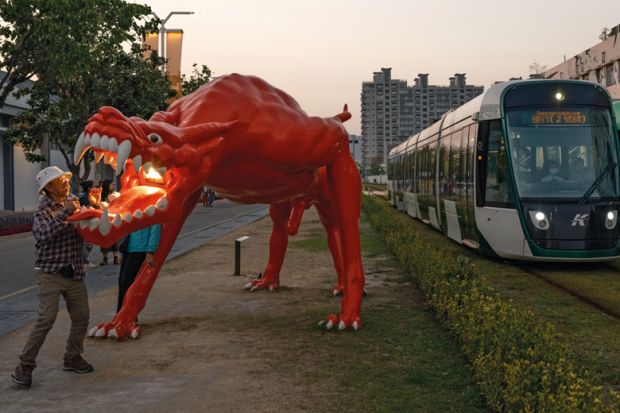 Dragon art installation outside the area of the Pier-2 Art Center in Kaohsiung, Taiwan with trams passing through to illustrate China ‘intimidating’ international academics travelling to Taiwan