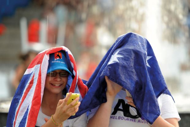 Spectators uses a flag to cover as rain stops play at the Australian Open tennis championship in Melbourne to illustrate delays