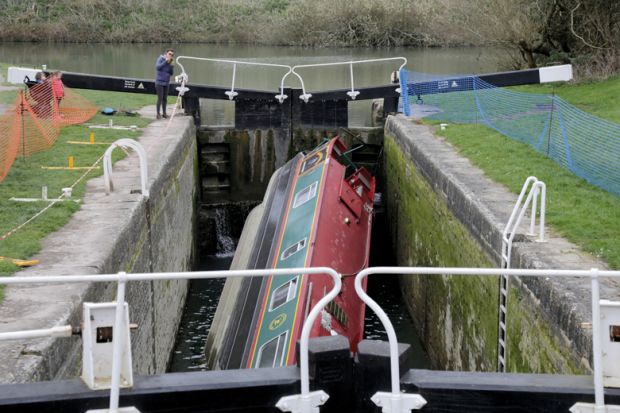 People look at a narrowboat that has capsized in a lock on the Kennet and Avon Canal 
