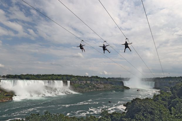 People ride a zip line on the Canadian side of the Niagara River to illustrate Canada ‘may fall short of caps’ as overseas interest nosedives