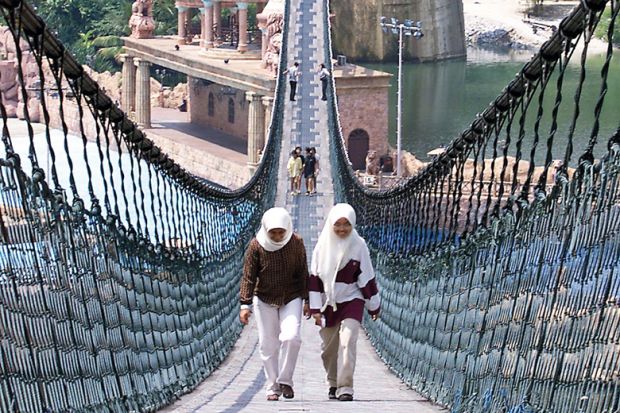 Two people walk on the world's longest pedestrian suspension bridge at Sunway Lagoon Theme Park in Kuala Lumpur to illustrate Flying high: how corporate-owned universities made a mark in Asia