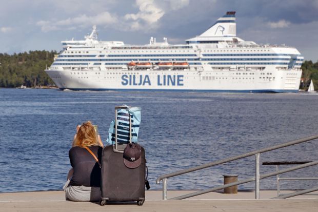 A woman is sitting on the quayside waiting for the boat with her luggage in  Lidingo, Sweden to illustrate Grant deadlines ‘create disparity’