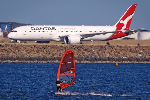 A sail boarder rides in front of a Qantas Airways plane to illustrate New Colombo Plan changes ‘will reverse equity gains’