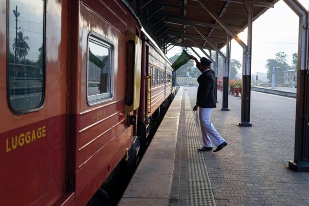 Train conductor giving wave with a green flag at Colombo fort train station to illustrate Professor departs South Asian University after Modi criticism row