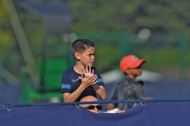 A tennis fan watches a game on his father shoulders over the fence n Surbiton, England to illustrate Reverse visa crackdown for ‘brightest and best’, says LBS dean