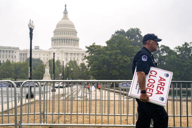 A U.S. Capitol police officer carries "Area Closed" signs in front of the U.S. Capitol  to illustrate Could US education department be shut?