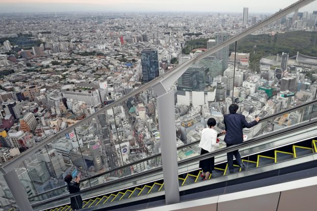 Visitors look out at the view while riding up an escalator at the Shibuya Sky observation deck in Tokyo to illustrate Students protest as Japanese universities mull tuition fee hikes