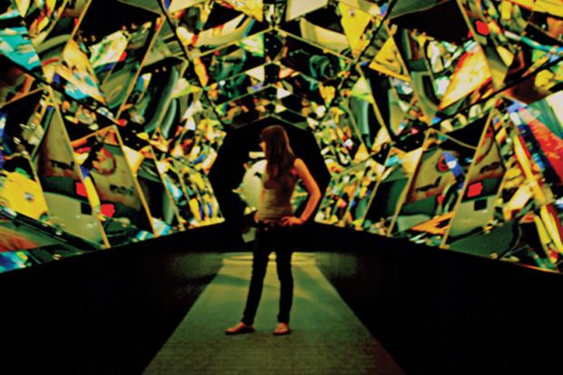 Young woman standing in hall of mirrors