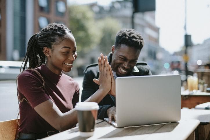 students hi fiving in front of computer