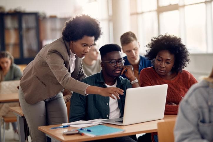 A group of black university students learning around a computer