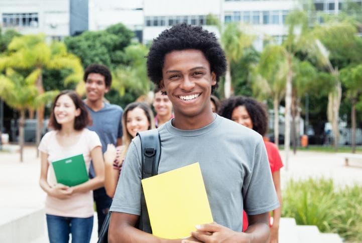 smiling dark skinned male student in front of other smiling students