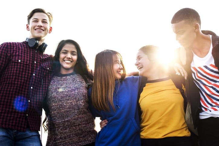 Group of students, outdoors, with their arms around one another, smiling