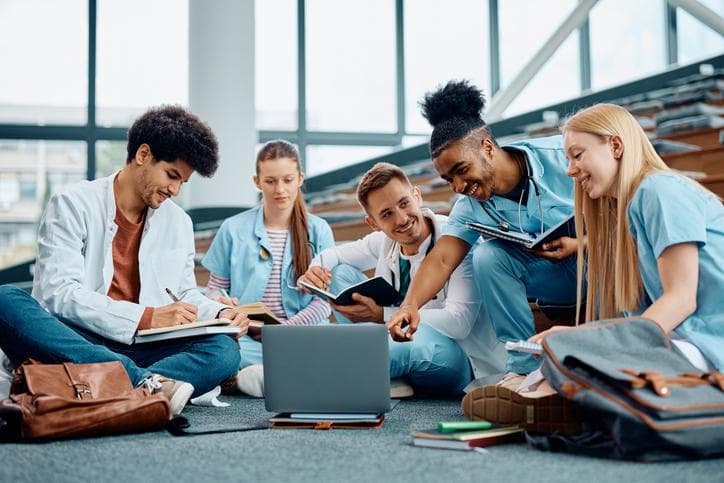 Group of happy medical students using laptop while learning in amphitheater